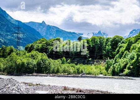 Paysage de montagne - forêt de montagnes, rochers glaciers nuages de neige, rivière au premier plan Dombay, Karachay-Cherkessia, Russie Banque D'Images