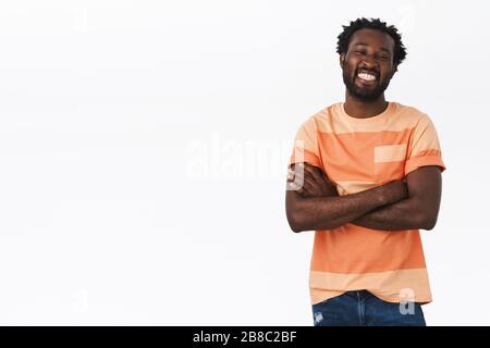Beau et joyeux jeune homme africain américain avec coupe de cheveux afro, barbe, croiser les mains sur la poitrine, rire, sourire heureux, profiter de la conversation drôle Banque D'Images