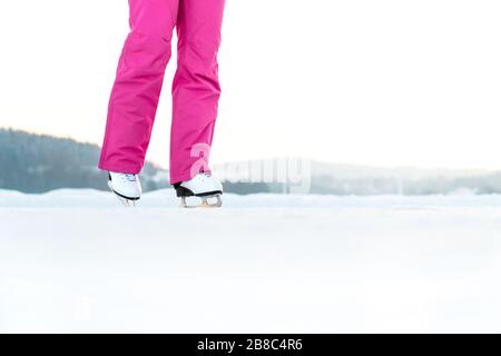 Patinage sur glace pour femme sur une piste extérieure. L'entraînement et l'entraînement de Skater en hiver. Patinage artistique sur un lac ou un étang. Espace de copie négatif. Banque D'Images