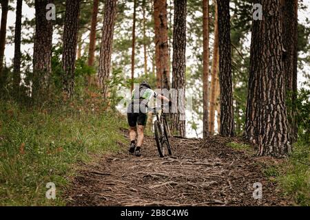 derrière le cycliste sale pour marcher sur le sentier forestier Banque D'Images