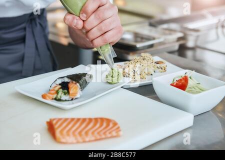 Chef japonais faisant des sushis au restaurant. Le chef sert des sushis japonais traditionnels servis sur une plaque en pierre blanche Banque D'Images