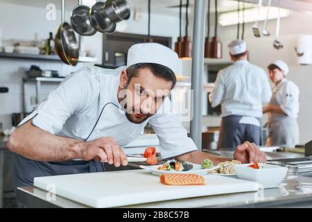 Chef faisant des sushis au restaurant. Il se concentre sur le service de sushis japonais traditionnels servis sur une plaque en pierre blanche. Concept de cuisson Banque D'Images