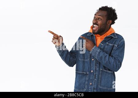 Enthousiaste, heureux et joyeux gars afro-américain en denim veste, orange sweat à capuche, se rendant excitant quand les vacances sont proches, célébrant Banque D'Images