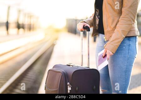 Femme attendant le train avec valise et bagages. Billet de la Dame et passeport à portée de main sur la plate-forme. Pistes en arrière-plan. Banque D'Images