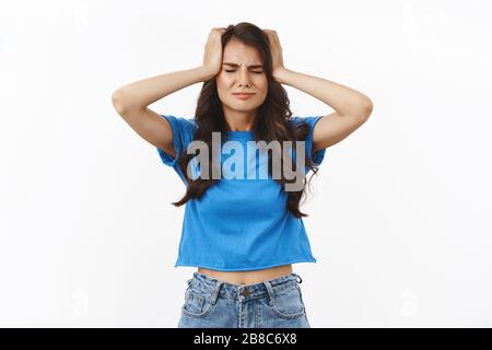 Fille a eu des choses bousillé, ne savez pas comment résoudre le problème qu'elle a fait. Troublé et frustré, la jeune femme brunette dans un t-shirt bleu, tenant la tête Banque D'Images