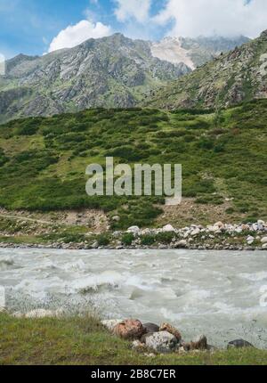 Vue sur la rivière Baspa en direction de l'Himalaya et des pentes rocheuses accidentées sous le ciel bleu en été près de Chitkul, Himachal Pradesh, Inde. Banque D'Images