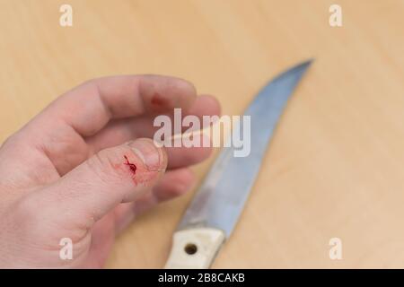 une goutte de sang sur le doigt d'une main qui a été accidentellement coupée avec un couteau Banque D'Images