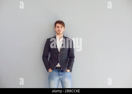 Jeune homme d'affaires étudiant de type dans des vêtements décontractés debout regardant sur fond gris. Homme d'affaires indépendant étudiant concepteur architecte personnes por Banque D'Images