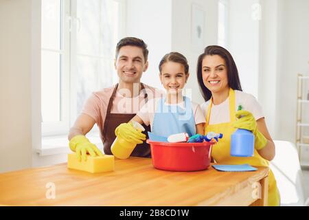 Une famille heureuse nettoie la chambre dans la maison. Mère père et petite fille enfant laver dans des gants tout en s'asseoir sur le sol souriant joyeux. Hygiène W Banque D'Images