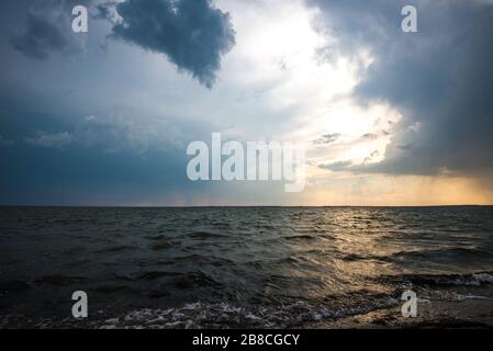 Coucher de soleil envoûtant parmi les nuages de cumulus au-dessus d'une mer calme lors d'une chaude soirée d'été. Le concept de la beauté de la nature et du temps Banque D'Images