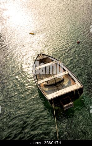 Amarré dans le port de Simon, un vieux bateau à ramer en bois baigne dans la lumière du soleil dorée de la fin de l'après-midi Banque D'Images