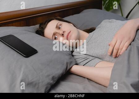 Gros plan bouleversé jeune femme couché dans le lit regardant sur smartphone se sent peur et peur, malheureux anxieux ayant des problèmes de relations difficultés Banque D'Images