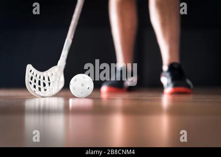 Joueur de floorball debout avec balle blanche et bâton. Concept de hockey sur sol. Banque D'Images