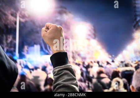 Protestation, soulèvement, mars ou grève dans la rue de la ville. Foule de gens qui marchent. L'homme à capuche proteste dans l'air. Militantisme pour l'égalité des droits de l'homme. Banque D'Images