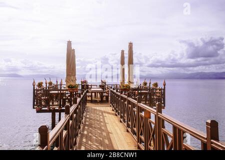 Longue jetée en bois avec café romantique au bout de la mer Ionienne. Grèce. Magnifique paysage, montagnes sur sealine. Journée ensoleillée avec des nuages sur l'île de Corfou. Banque D'Images