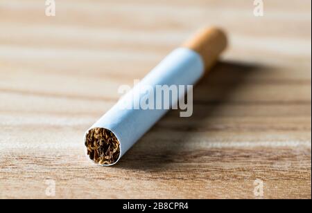 Cigarette sur table en bois, vue macro gros plan. Tabac, papier et nicotine. Cessez de fumer. Banque D'Images