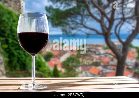 Verre de vin sur fond de flou de mer et vieille ville méditerranéenne en Croatie Banque D'Images