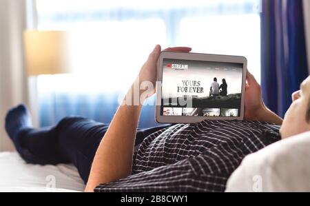 Service de films, de vidéos et de streaming en ligne sur tablette. Homme choisissant et regardant un film numérique avec un appareil intelligent. Personne se reposant. Accès Internet par réseau TV. Banque D'Images
