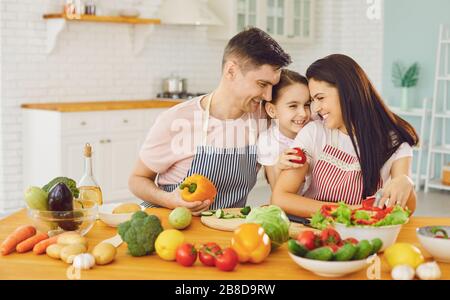 Famille heureuse avec fille dans la cuisine avec légumes. Banque D'Images