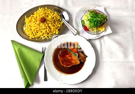 Plat bavarois traditionnel 'Schweinebrarten' (porc rôti) avec salade mixte et 'Spätzle', une sorte de nouilles allemandes du sud Banque D'Images