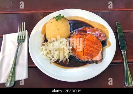 Plat traditionnel bavarois « Schweinebrarten » (porc rôti) avec salade de kraut et boulettes de pommes de terre Banque D'Images