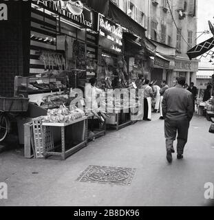 1967, rue latérale à Nice, France, montrant des magasins de nourriture, y compris une Boucherie qui affiche à l'extérieur de ses produits. Banque D'Images