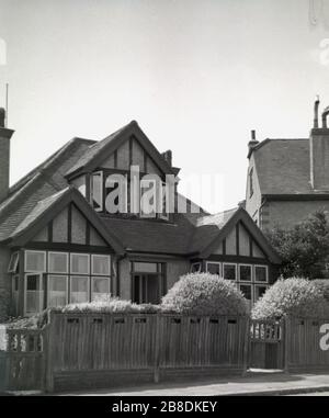 1953, vue historique et extérieure d'une petite maison de banlieue construite dans les années 1920-1930, derrière une clôture en bois, de style similaire à un bungalow, mais avec un étage supérieur ou deuxième, construite dans le toit en pente, souvent appelé "chalet bungalow", à cause du loft de deuxième étage, Angleterre, Royaume-Uni. En tant que conception architecturale, ils étaient particulièrement populaires en Grande-Bretagne entre les deux guerres mondiales, particulièrement dans les zones suburbaines et côtières. Banque D'Images