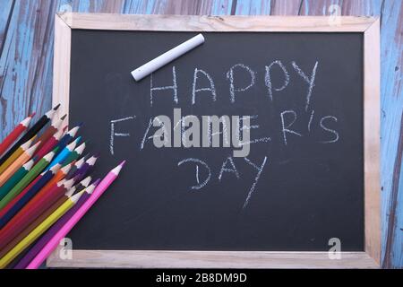 Crayons et tableau de surveillance avec des mots HAPPY PALEUR JOUR sur fond en bois, Banque D'Images