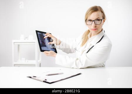 Médecin féminin montrant la colonne vertébrale des rayons X sur la tablette numérique