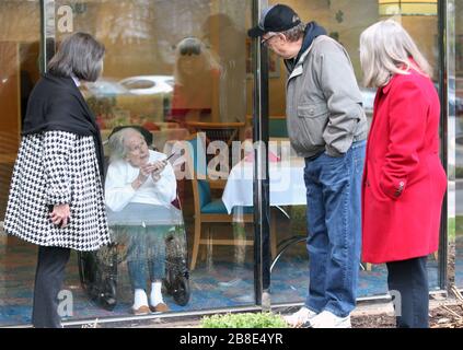 Ballwin, États-Unis. 21 mars 2020. Wilma Grove utilise un téléphone portable pour parler à ses enfants (de L à R) Judy Kekich, Ed Grove et Pat Grove lors d'une visite aux jardins Delmar sur les verts à Ballwin, Missouri, le 21 mars 2020. La famille a été forcée de rendre visite à sa mère de 100 ans chaque jour de l'extérieur en raison des préoccupations de Coronavirus. Les cas connus du Missouri de COVID-19, est à 73 y compris trois morts.photo par Bill Greenblatt/UPI crédit: UPI/Alay Live News Banque D'Images