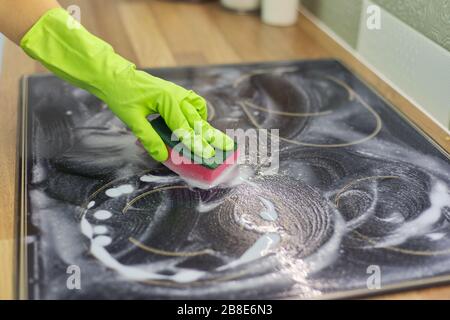 Gros plan de femme à la main nettoyage de la surface électrique moderne en céramique de verre de cuisson avec éponge et détergent Banque D'Images