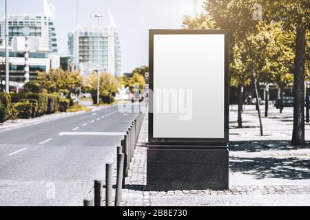 Mockup d'une affiche d'information vide en milieu urbain près d'une route de la ville; un modèle de bannière verticale vierge sur le trottoir en allée Banque D'Images