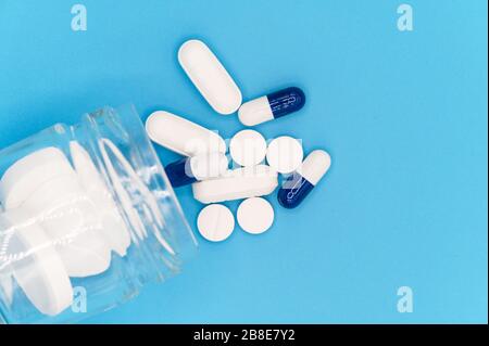 Gros plan de pilules qui débordent de la bouteille de pilules sur fond bleu. Avec espace de copie. Concept de médecine . Vue de dessus . Banque D'Images