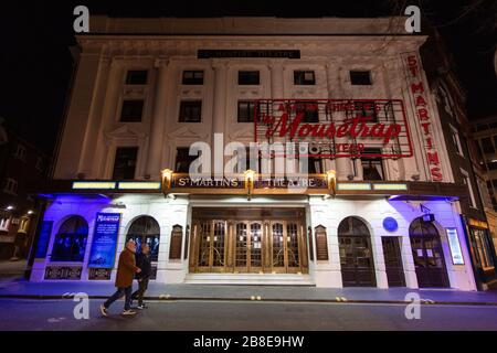 Les gens marchent devant les portes fermées du St Martin's Theatre London, qui abrite le 'The Mousetrap' d'Aghata Christie, Ce qui est le plus long jeu de course continue au monde, le jour où le premier ministre Boris Johnson a ordonné la fermeture de théâtres, de pubs et de restaurants dans tout le pays, à l'heure où le gouvernement a annoncé des mesures sans précédent pour couvrir les salaires des travailleurs qui perdraient autrement leur emploi en raison de l'épidémie de coronavirus. Banque D'Images