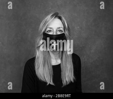 photographie noir et blanc. Pleurer une femme âgée portant un masque noir pour protéger contre une épidémie de virus covid, corona. Banque D'Images