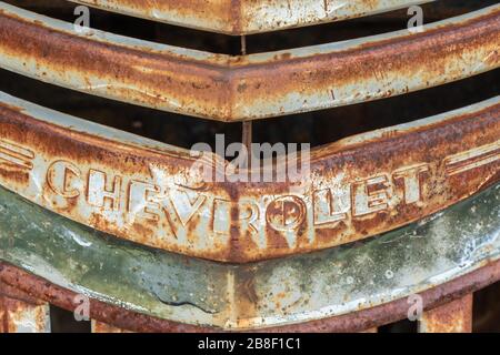 Ancienne grille de Chevrolet rouillée sur une voiture épave dans une cour de jonque Banque D'Images
