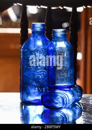 Trois bouteilles de lait vides de bleu magnésie placées sur une étagère réfléchissante. Fabriqué en Amérique gaufré sur le fond Banque D'Images