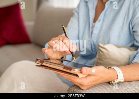 Gros plan des mains de la femme tenant une tablette PC et un stylet Banque D'Images