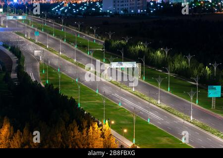 Vue de nuit sur l'autoroute Archabil avec huit voies de large à Ashgabat, au Turkménistan. Superbes ornements dans les poteaux de lampe et les panneaux de signalisation. Banque D'Images