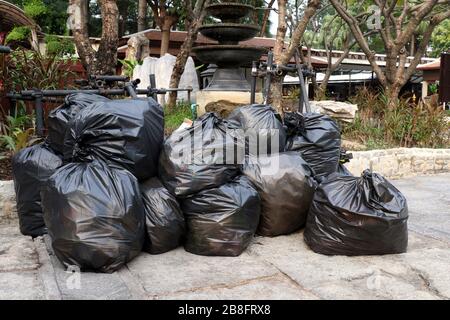 déchets tas de déchets sacs noirs pile plastique sur le sol du parc public, beaucoup de déchets noirs déchets sacs plastique pile Banque D'Images