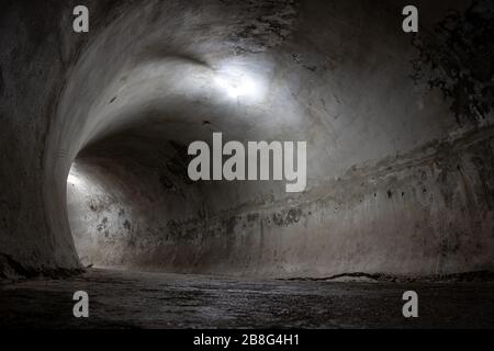 Tunnel sombre forme ronde légèrement éclairée avec des ampoules. Banque D'Images