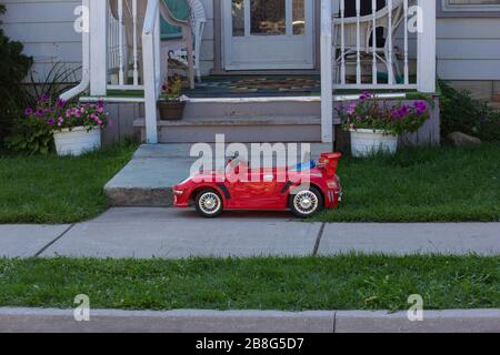 Voiture jouet rouge devant une petite maison de ville Banque D'Images