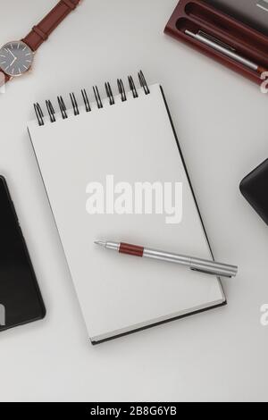 Arrière-plan minimaliste et détaillé de l'espace de travail, ordinateur portable en spirale ouvert avec feuille vierge, stylo et téléphone portable. Espace de copie vue de dessus, plat, maquette. Banque D'Images