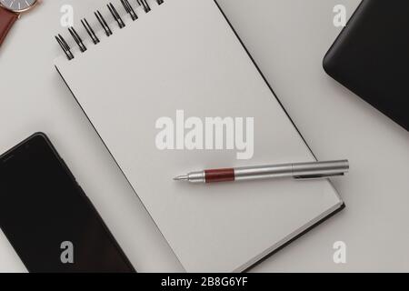 Arrière-plan minimaliste et détaillé de l'espace de travail, ordinateur portable en spirale ouvert avec feuille vierge, stylo et téléphone portable. Espace de copie vue de dessus, plat, maquette. Banque D'Images