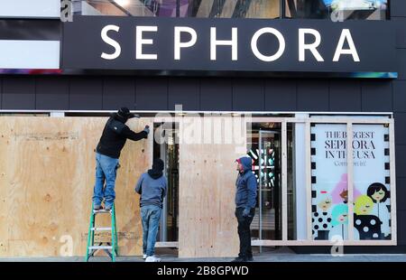 New York, États-Unis. 21 mars 2020. Les travailleurs bloquent les fenêtres et les portes avec des panneaux de bois dans un magasin Sephora sur Times Square à New York, aux États-Unis, le 21 mars 2020. Le gouverneur de l'État américain de New York, Andrew Cuomo a déclaré samedi qu'un total de 10 356 personnes dans l'État avaient testé positif pour le nouveau coronavirus, sautant 3 254 par rapport à la veille. Vendredi, Cuomo a annoncé qu'un mandat, qui exige que les personnes travaillant dans des entreprises non essentielles restent à la maison, entrera en vigueur dimanche soir. Crédit: Wang Ying/Xinhua/Alay Live News Banque D'Images