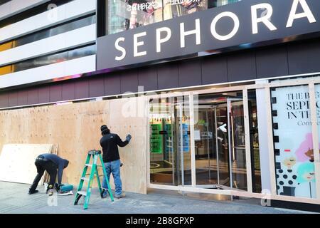 New York, États-Unis. 21 mars 2020. Les travailleurs bloquent les fenêtres et les portes avec des panneaux de bois dans un magasin Sephora sur Times Square à New York, aux États-Unis, le 21 mars 2020. Le gouverneur de l'État américain de New York, Andrew Cuomo a déclaré samedi qu'un total de 10 356 personnes dans l'État avaient testé positif pour le nouveau coronavirus, sautant 3 254 par rapport à la veille. Vendredi, Cuomo a annoncé qu'un mandat, qui exige que les personnes travaillant dans des entreprises non essentielles restent à la maison, entrera en vigueur dimanche soir. Crédit: Wang Ying/Xinhua/Alay Live News Banque D'Images