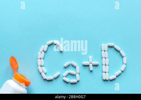 Comprimés génériques de calcium et de vitamine D. Pilules blanches formant la forme à l'alphabet Ca+D sur fond bleu, espace de copie, vue de dessus. Banque D'Images