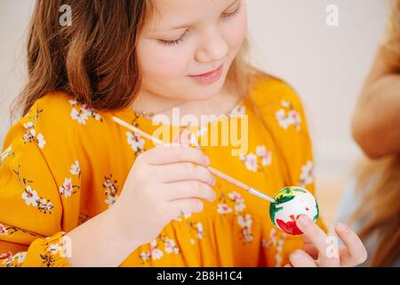 Bonne fille a participé à la peinture de l'oeuf de pâques à l'aide de la brosse Banque D'Images