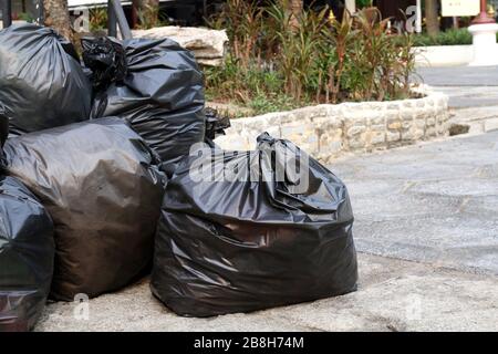 Déchets de plastique, beaucoup de tas de sacs de déchets noirs empilent sur le sol du parc public, beaucoup de déchets noirs empilent des sacs de plastique Banque D'Images