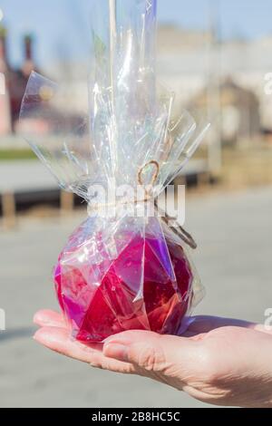 pomme caramel rouge sur la main femelle à l'extérieur Banque D'Images